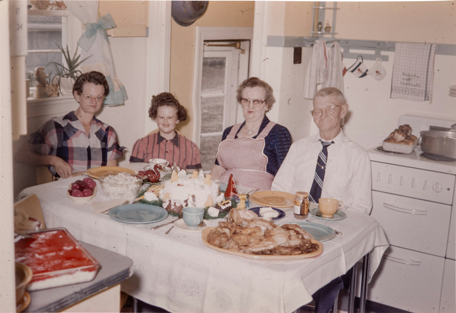 A family gathered around a dinner table in the early 1970s. The watchers are present.